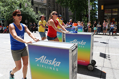 Members pushing Alaska Airlines cart with free swag.