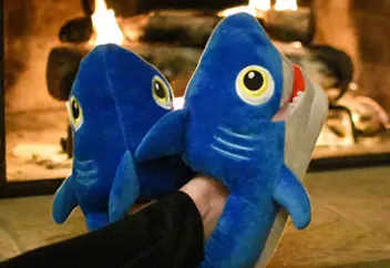 Custom made shark plush booties worn in front of a fireplace